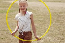 Chica mirando a través de hula hoop sonriendo a la cámara - foto de stock