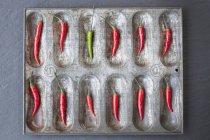 Chiles rojos y un chile verde en lata para hornear - foto de stock