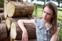 Teenage girl leaning on logs in forest — Stock Photo