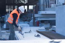 Fabrikarbeiter befestigt Windenhaken an Betonblock in Betonbewehrungsfabrik — Stockfoto