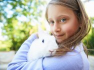 Primer plano de niña sosteniendo conejo de mascota - foto de stock
