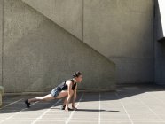 Jovem mulher se alongando na frente da parede de concreto — Fotografia de Stock