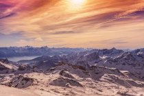 Luz do pôr do sol sobre montanhas cobertas de neve — Fotografia de Stock