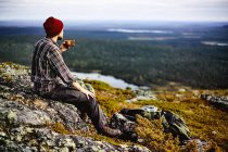 Male hiker overlooking landscape with coffee, Lapland, Finland — Stock Photo