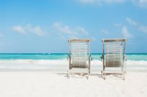 Deux chaises longues sur la plage de sable blanc — Photo de stock