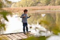 Хлопчик стоїть на пірсі і рибалить у річці — стокове фото