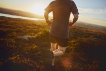 Cropped shot of mature athlete running in rural landscape — Stock Photo