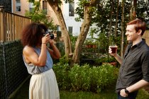 Woman photographing man in garden — Stock Photo