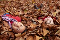 Bambini che giocano in foglie d'autunno — Foto stock