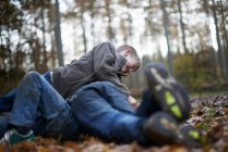 Meninos jogam luta no chão da floresta no outono — Fotografia de Stock