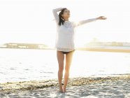 Young woman on sunlit beach with arm out, Port Melbourne, Melbourne, Victoria, Australia — Stock Photo