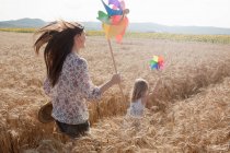 Madre e hija corriendo a través del campo de trigo - foto de stock