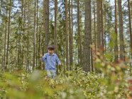 Junge läuft mit Stock durch Wald — Stockfoto