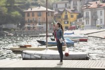 Mujer joven parada en el muelle comiendo helado en el lago Mergozzo, Verbania, Piamonte, Italia - foto de stock
