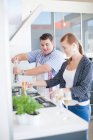Young man and woman cooking in kitchen — Stock Photo