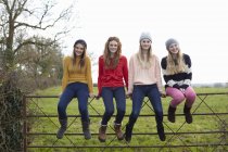 Four teenage girls sitting on gate — Stock Photo