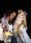 Junge Frauen zusammengekauert, Einmachgläser mit offenem Mund lächelnd — Stockfoto