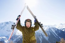 Garçon tenant des skis au-dessus de sa tête — Photo de stock