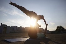 Zwei silhouette junge Frauen praktizieren Yoga auf einem städtischen Parkplatz — Stockfoto