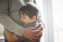 Father and son hugging by window, cropped — Stock Photo