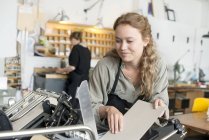 Женщина-принтер вставляет бумагу в машину в мастерской — стоковое фото