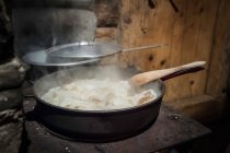Panela de guisado cozinhar no fogão com colher de madeira — Fotografia de Stock