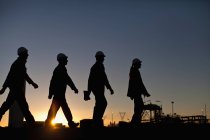 Silhouette of workers at oil refinery — Stock Photo