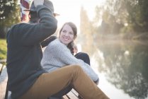 Jovem casal sentado junto ao rio — Fotografia de Stock