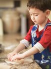 Child kneading dough with rolling pin — Stock Photo
