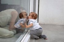 Mother and son kissing through glass — Stock Photo