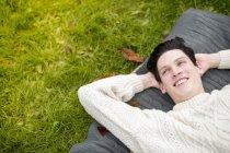 Молодой человек лежит на ковре в свитере — стоковое фото