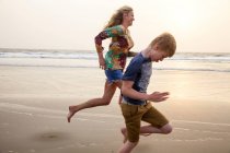 Madre e hijo corriendo en la playa - foto de stock