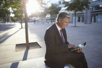 Empresário sentado do lado de fora e usando tablet digital — Fotografia de Stock