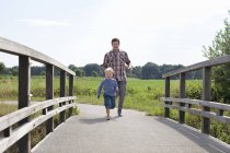 Padre e hijo corriendo sobre puente de madera - foto de stock