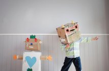 Robot de cartón y niño en máscara de robot - foto de stock