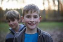 Портрет хлопчиків, які дивляться в камеру в лісі під підсвічуванням — стокове фото