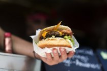 Man's hand serving hamburger from fast food van — Stock Photo