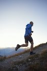 Trail runner running uphill, Valais, Suiza - foto de stock