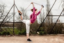 Frau im Kapuzenpulli zieht Pilates-Seil hinter gebeugtem Bein — Stockfoto
