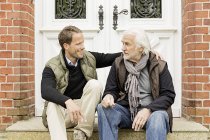 Father and son sitting on doorstep — Stock Photo