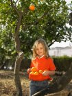 Young girl holding oranges — Stock Photo