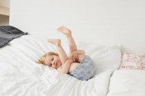 Портрет девочки, играющей на кровати — стоковое фото