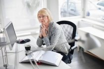 Businesswoman sitting at desk — Stock Photo