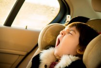 Young girl with eyes closed yawning in car — Stock Photo