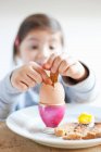Girl dipping toast into egg at breakfast — Stock Photo