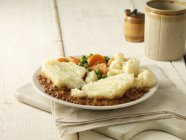 Plate of cottage pie with cauliflower, peas and carrots — Stock Photo