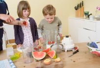 Menino e menina preparando smoothies frutas — Fotografia de Stock