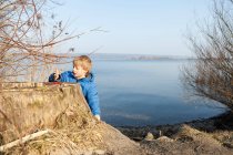 Boy playing with berries by lake — Stock Photo
