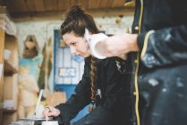 Vista lateral de mujer joven en taller removiendo esmalte de cerámica, mirando hacia otro lado - foto de stock