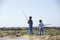 Due giovani ragazzi, pesca in spiaggia, vista posteriore — Foto stock